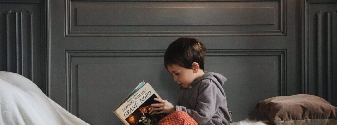 boy in gray jacket reading book