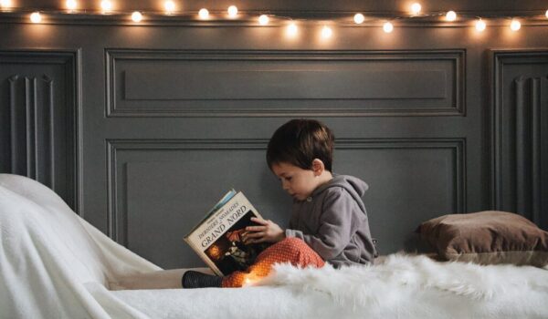 boy in gray jacket reading book